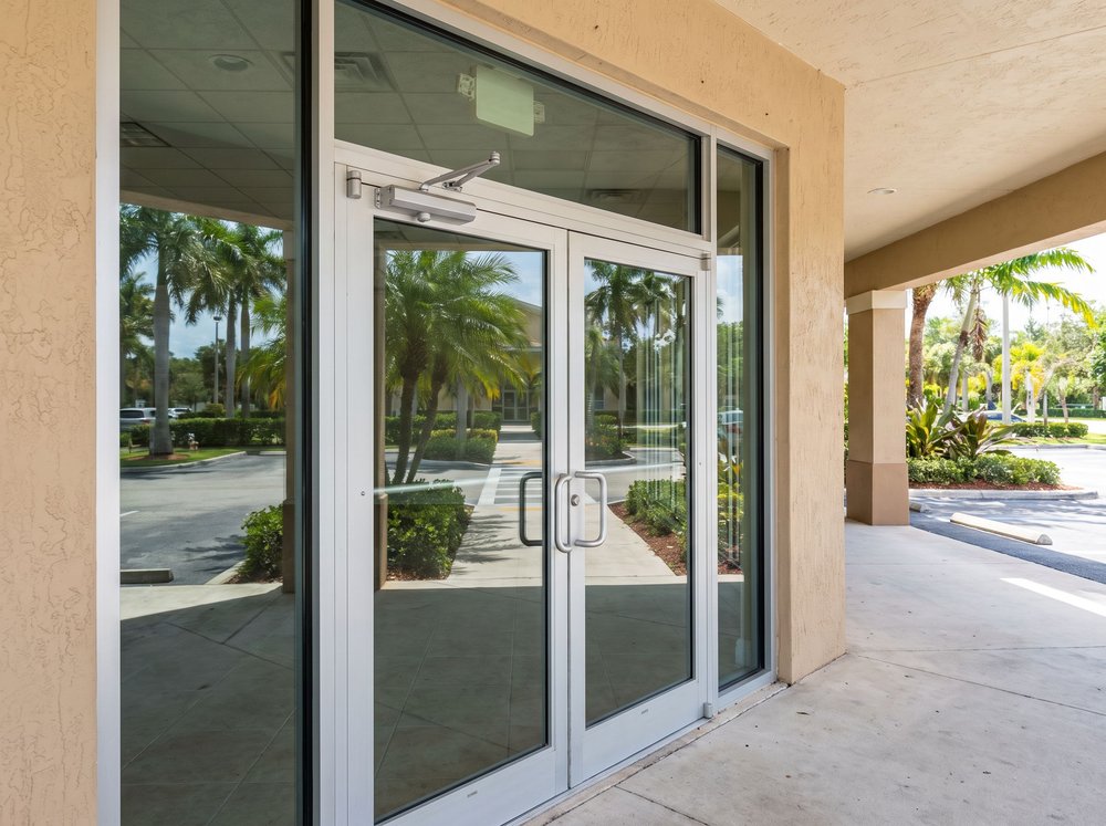 The same commercial storefront glass door after repair, with the closer arm reconnected and adjusted and the door hanging square in its frame