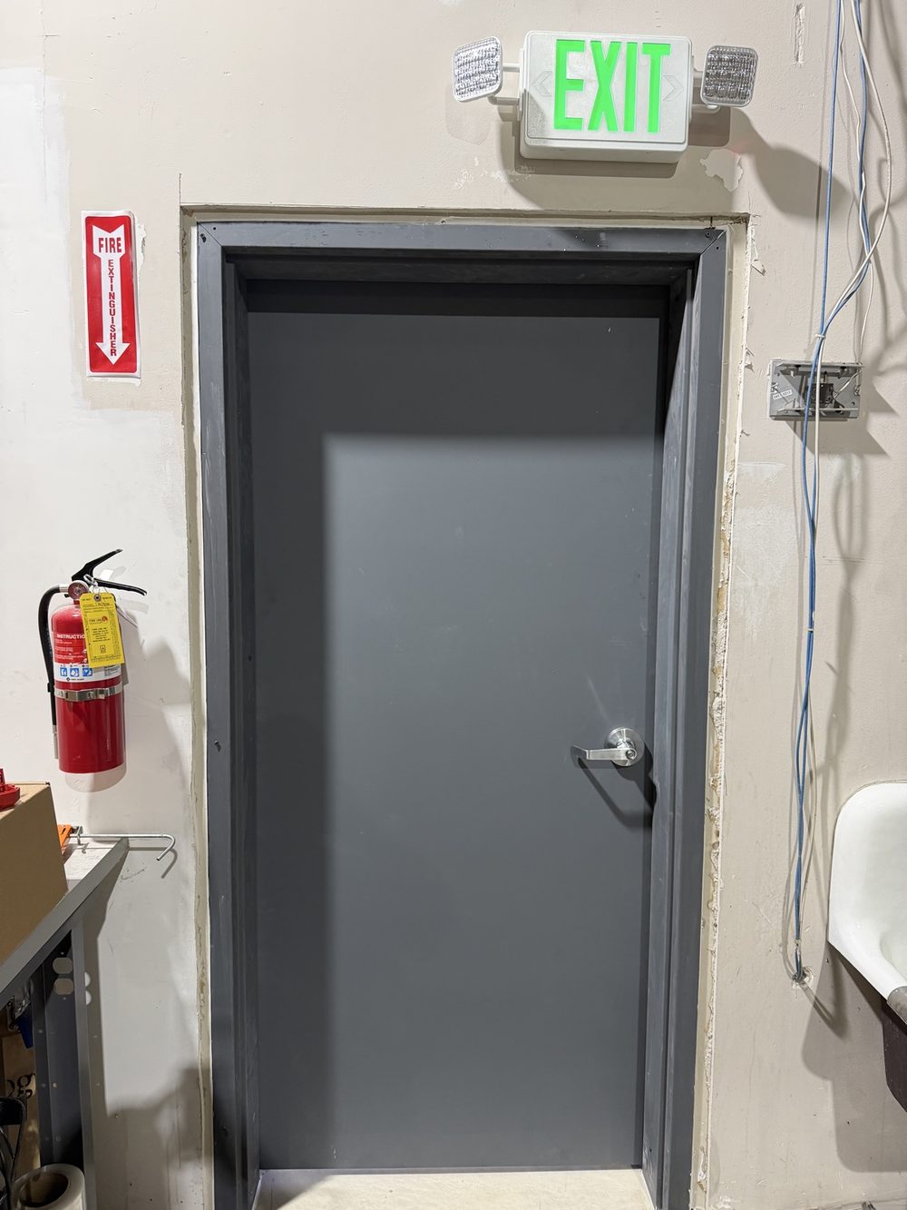 Newly installed gray fire-rated door with exit sign