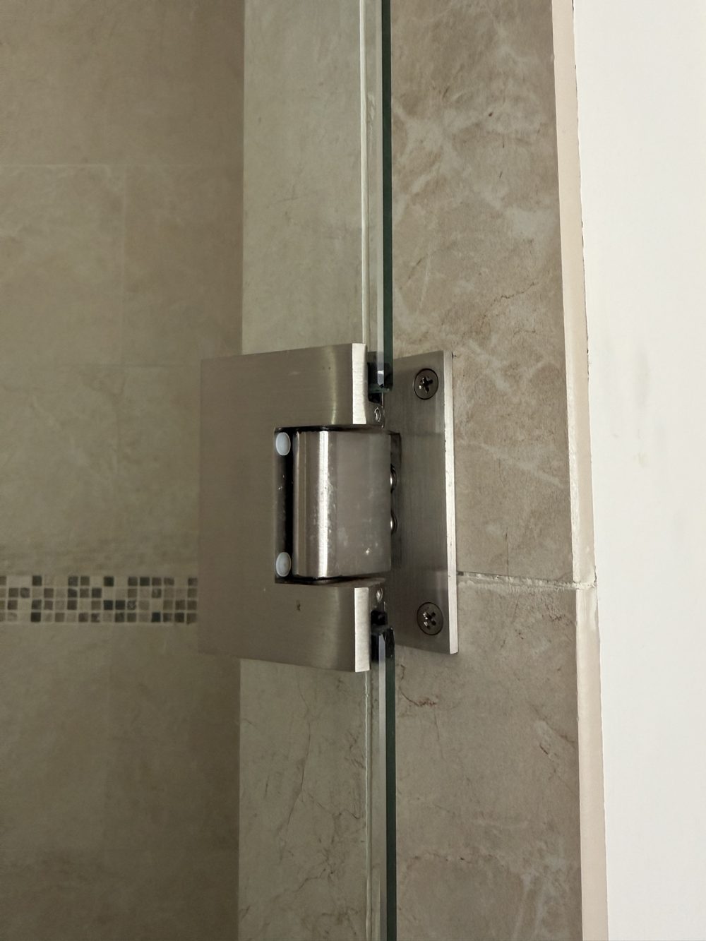 Wall-mounted hinge on a frameless shower door